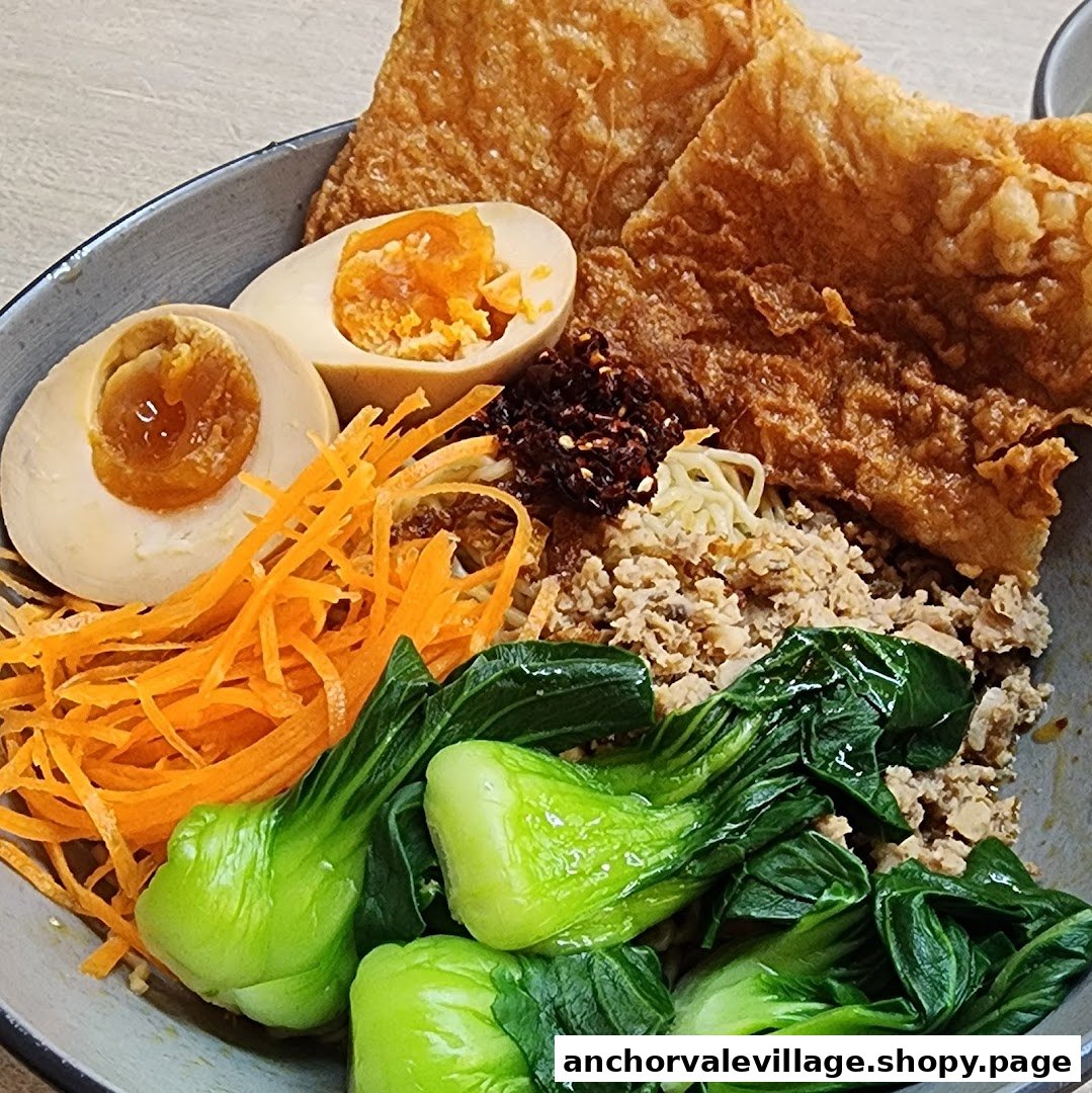 A vibrant bowl of vegetarian noodles with bok choy, shredded carrots, eggs, and crispy tofu skin.