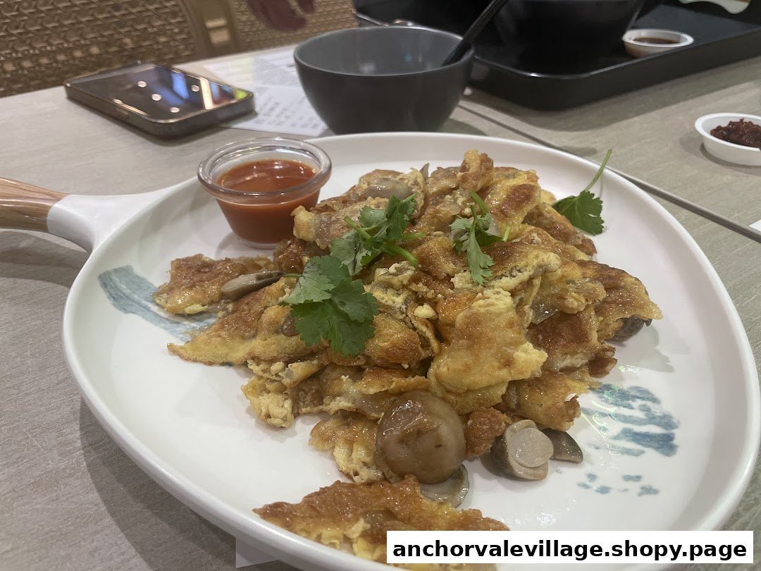 A close-up of a golden fried egg dish with mushrooms and cilantro, served with chili sauce.
