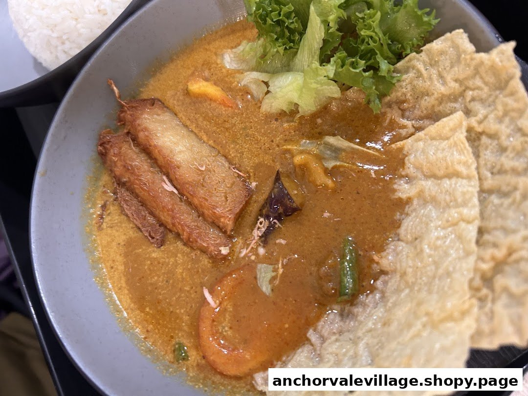 A vibrant bowl of vegetarian curry with tofu skin, vegetables, and a side of rice.
