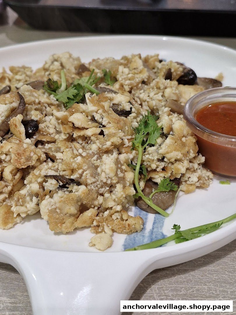 A close-up of a vegetarian dish with mushrooms and a side of chili sauce.