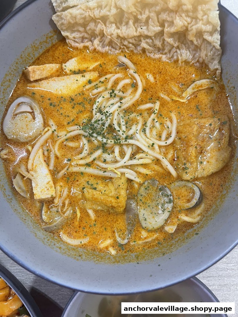 A vibrant bowl of vegetarian curry noodles with tofu, mushrooms, and crispy beancurd skin.