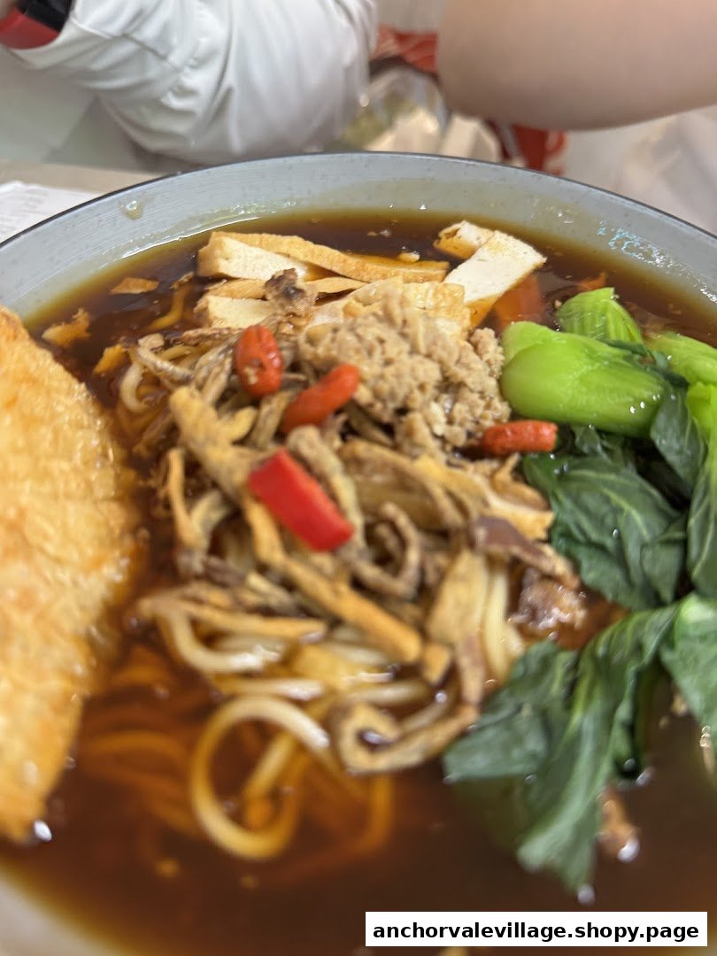 A close-up of a hearty bowl of vegetarian noodles with various toppings and rich broth.