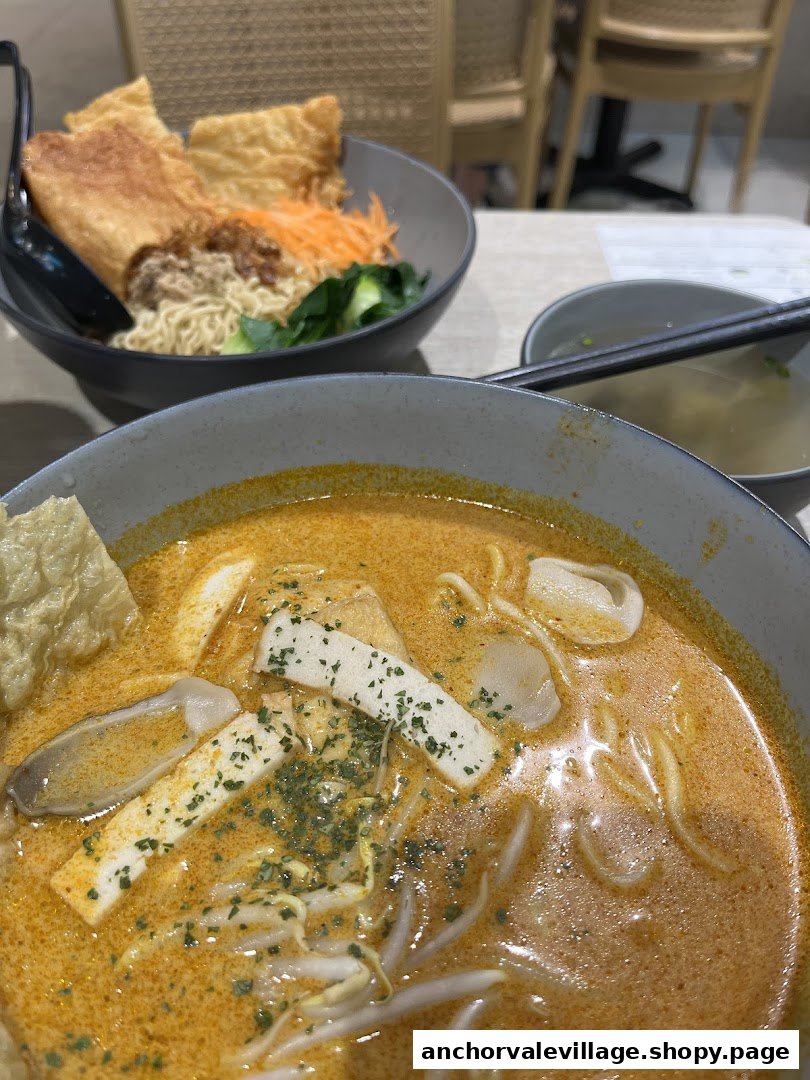 Two bowls of delicious vegan noodles, including a rich laksa, served on a table.