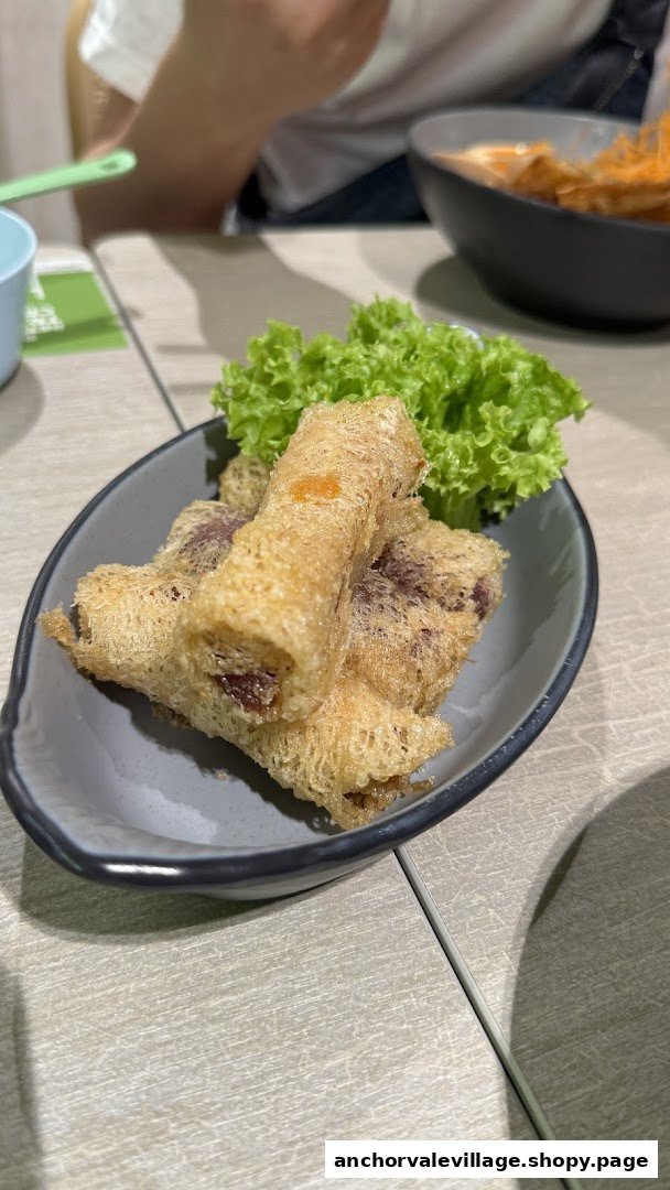 A plate of crispy fried rolls with lettuce on a table at Saute Mee.