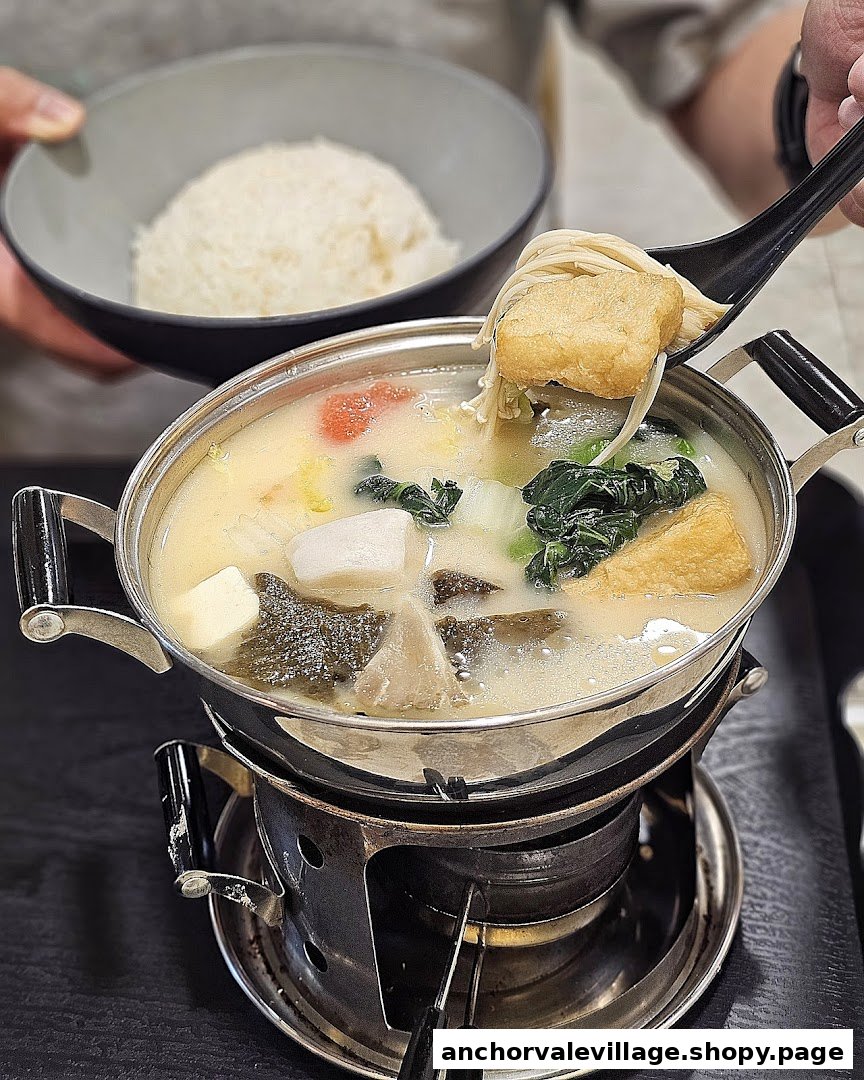 A hotpot with various vegetables and tofu, served with rice, being enjoyed.