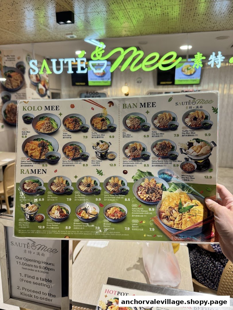 A hand holds up a menu displaying various vegan noodle dishes and hotpots from Saute Mee.