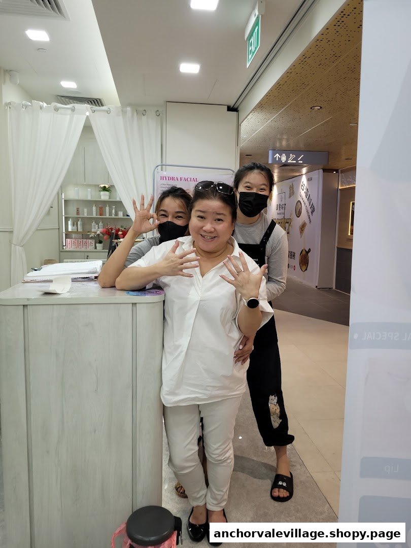 Three friendly staff members smiling and posing inside a bright beauty and wellness shop, featuring a Hydra Facial sign.