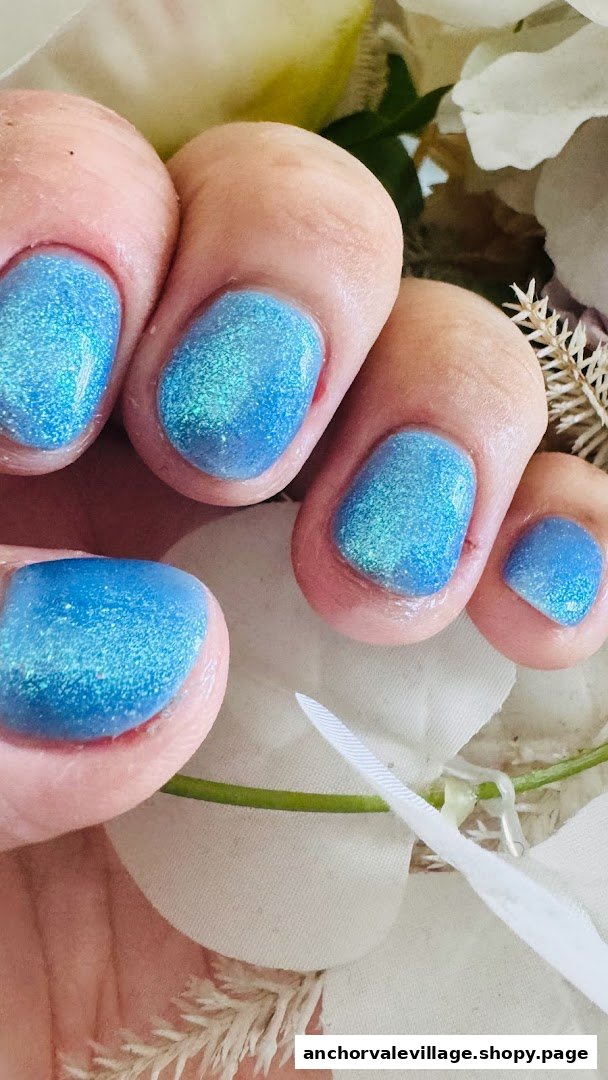 Close-up of fingers with vibrant blue glitter nail polish, showcasing a fresh manicure.