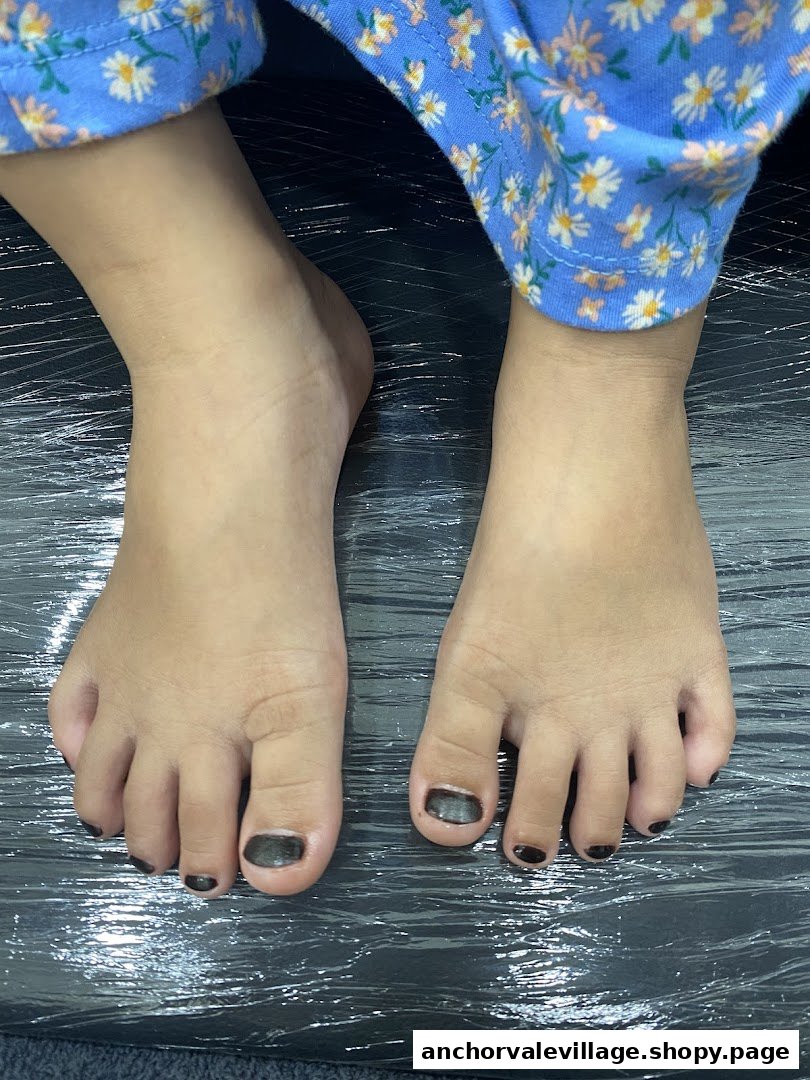 Close-up of a child's feet with dark nail polish, likely during a pedicure service.