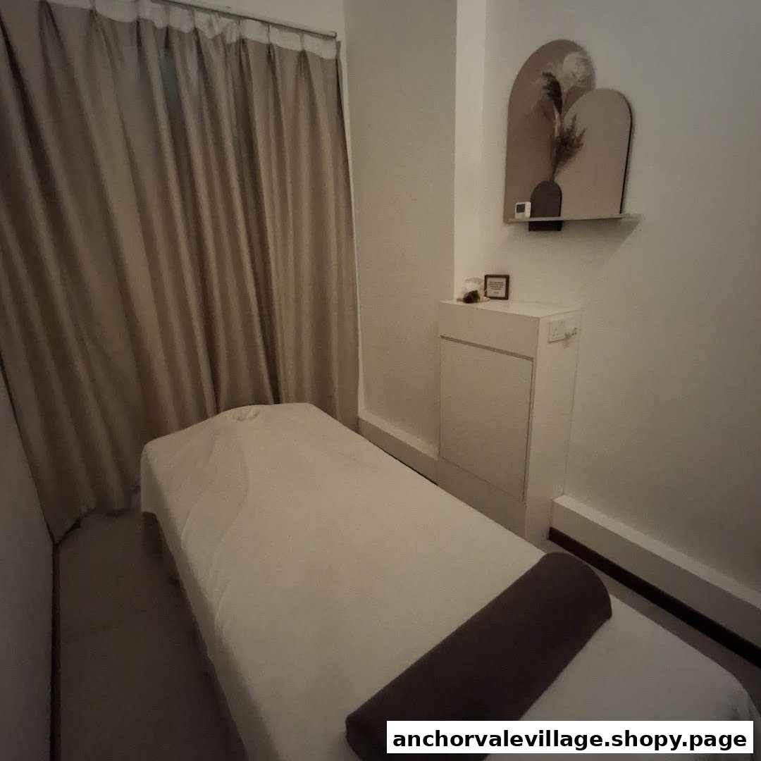 A serene treatment room featuring a massage bed, soft curtains, and minimalist decor.