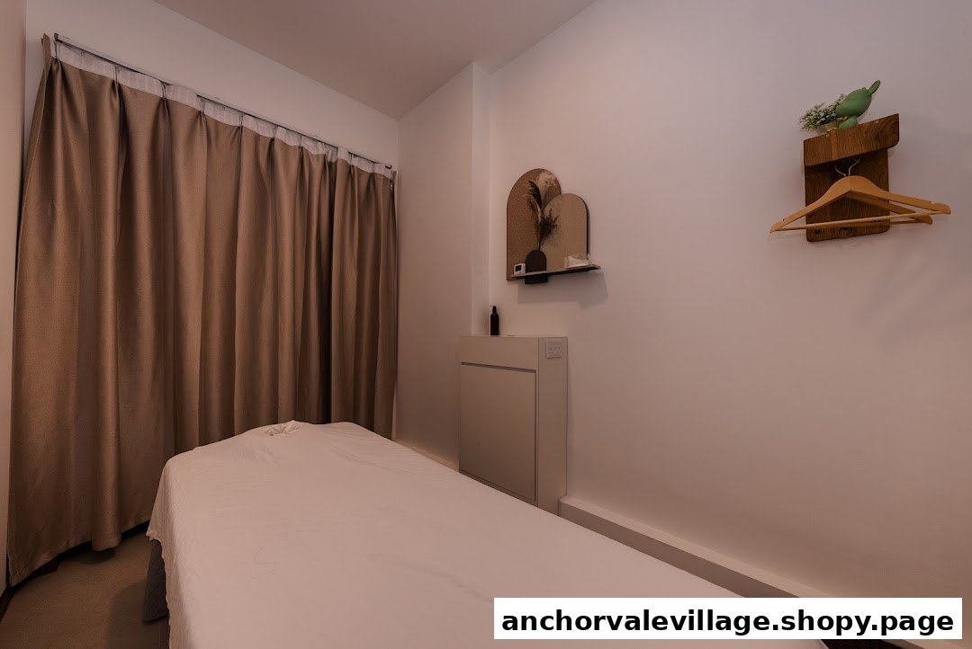 A serene and minimalist treatment room with a massage bed, curtains, and subtle decor.