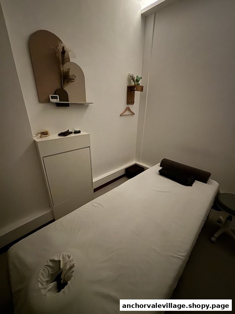A serene, minimalist treatment room with a massage bed and subtle decor.