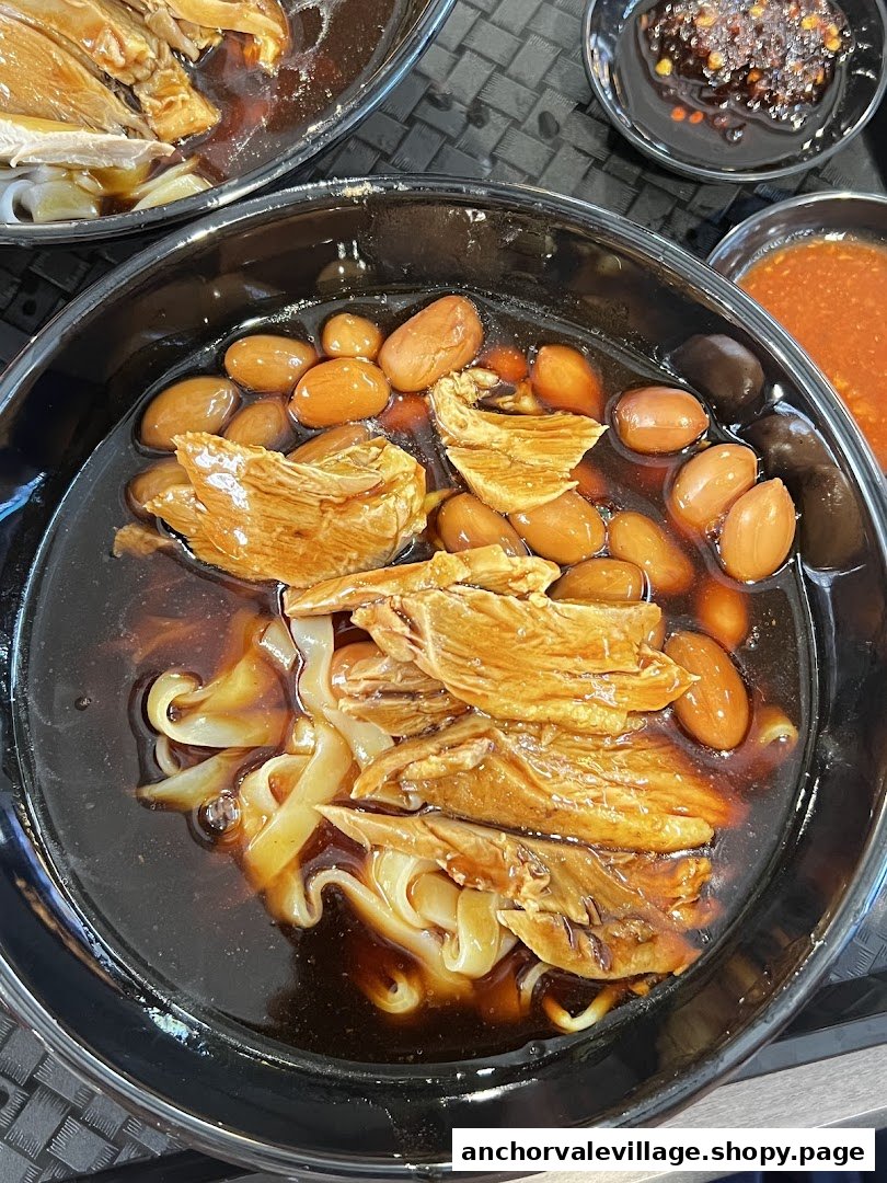 A close-up of a delicious bowl of Kway Chap with duck meat, peanuts, and flat rice noodles.