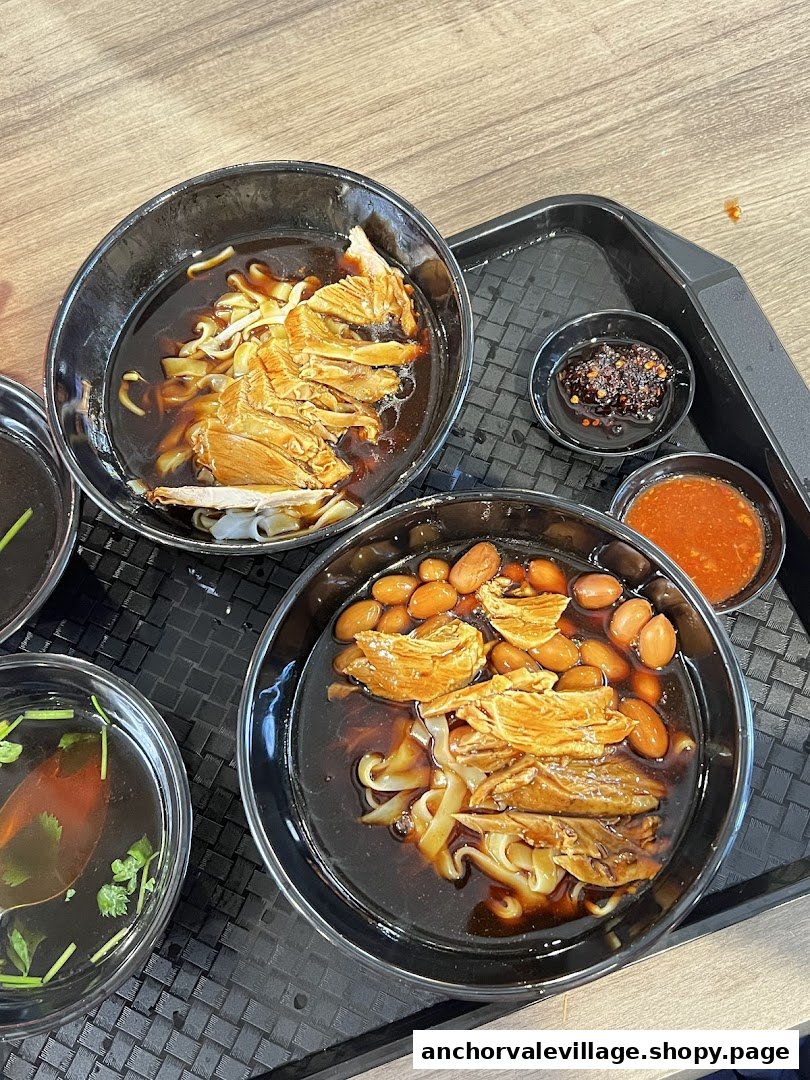 Two bowls of delicious Kway Chap with duck, noodles, and peanuts, served with chili.