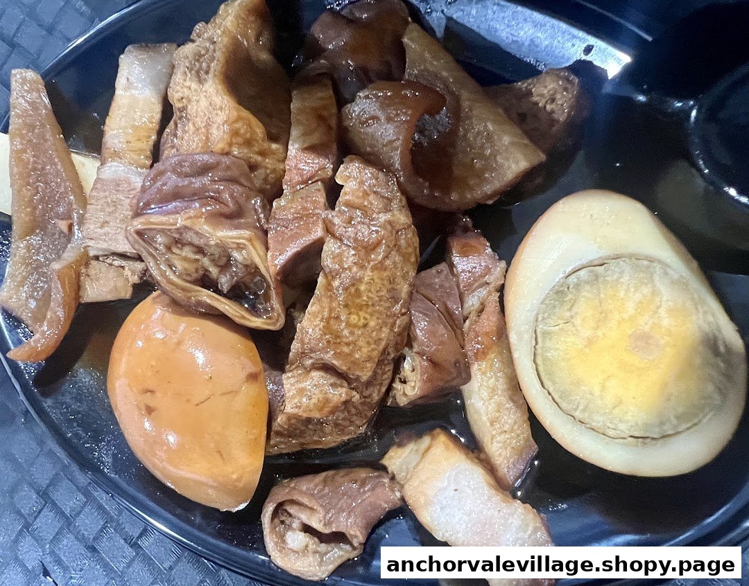 A close-up of a delicious plate of braised pork, offal, and eggs in a savory sauce.