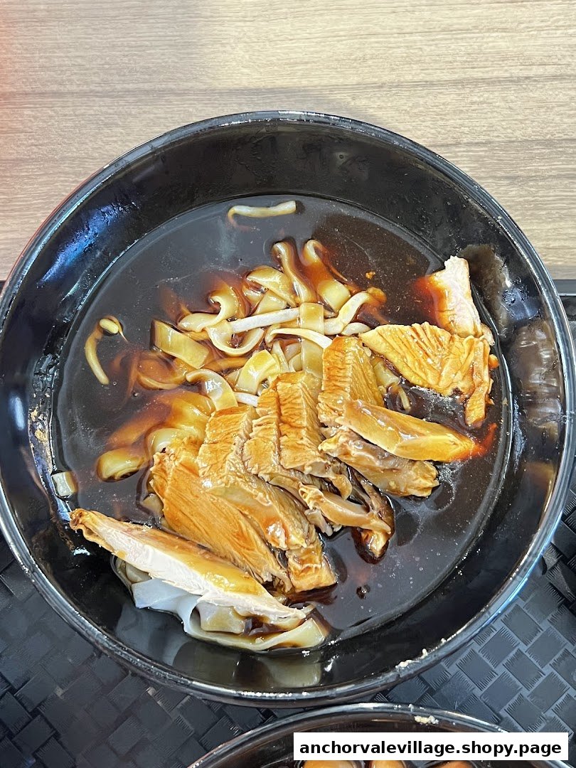A close-up of a delicious bowl of Kway Chap with sliced duck meat in a rich broth.