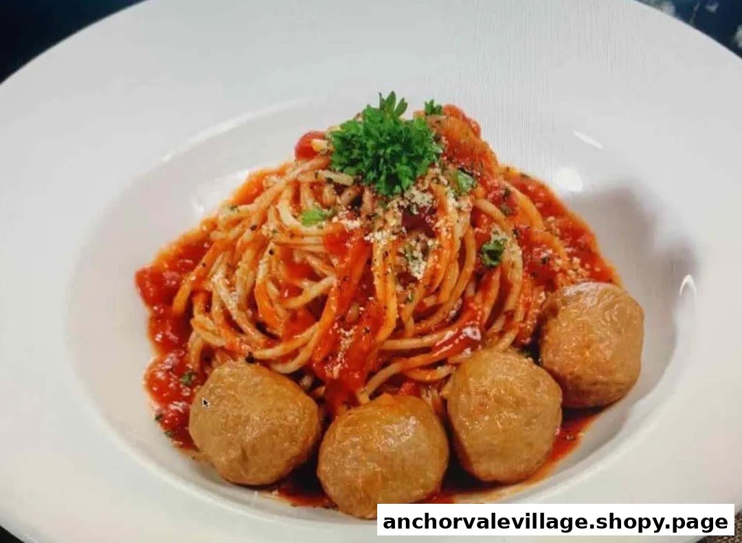 A close-up of a plate of spaghetti with tomato sauce and meatballs, garnished with parsley and cheese.