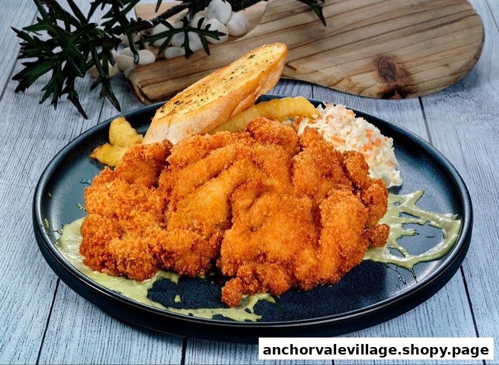 A plate of crispy fried chicken cutlets with garlic bread, fries, and coleslaw.