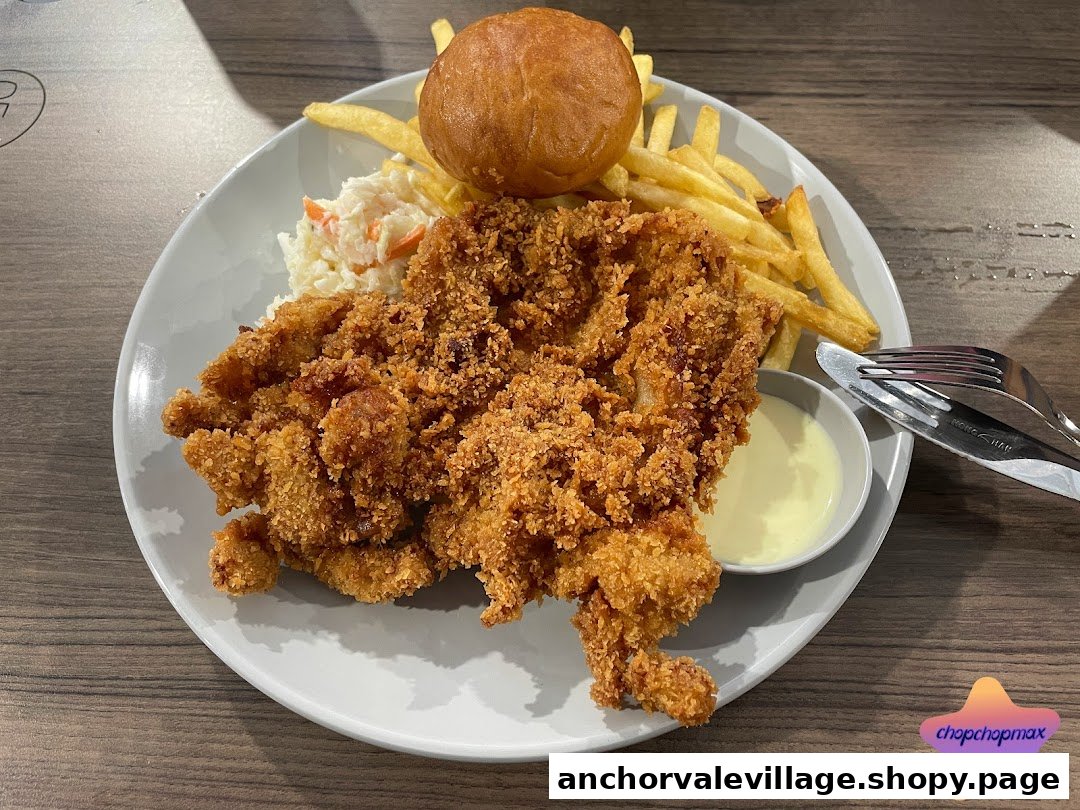 A plate of crispy fried chicken with fries, coleslaw, a bun, and dipping sauce.