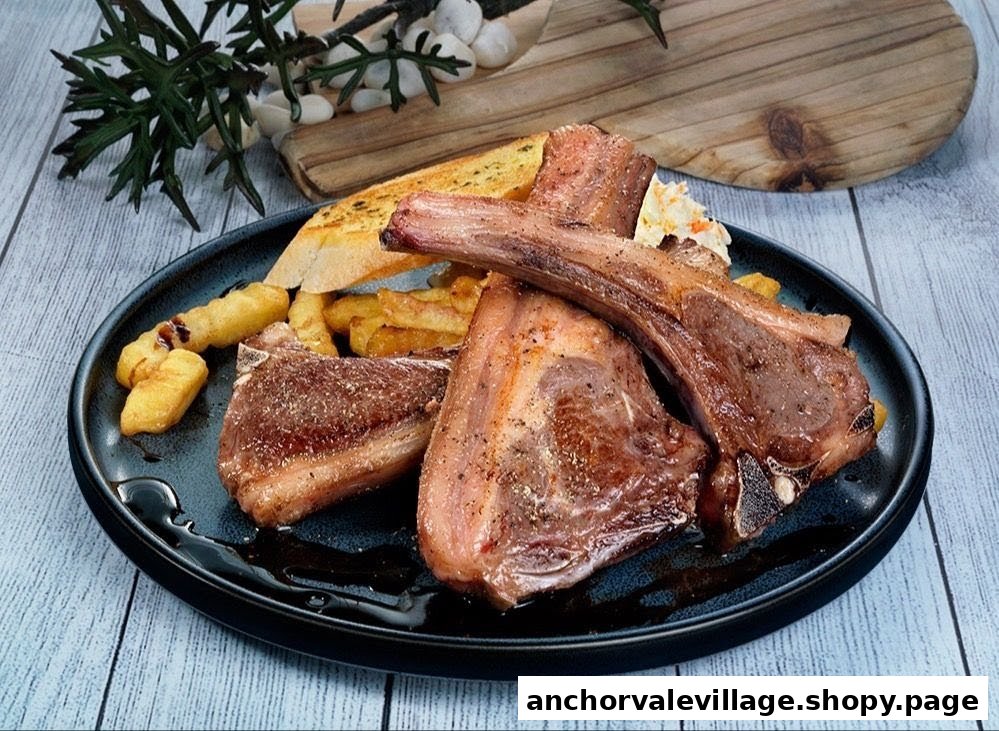 A plate of grilled lamb chops served with golden fries, garlic bread, and coleslaw.