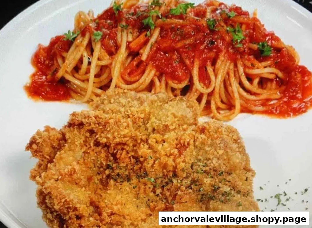 A plate featuring crispy breaded chicken cutlet served with spaghetti in tomato sauce.