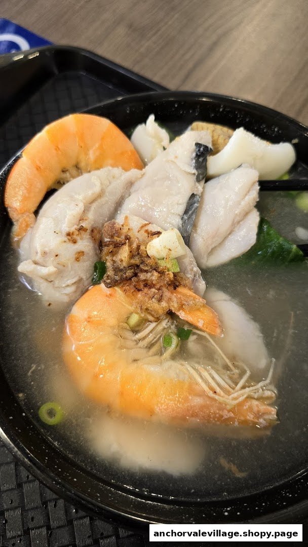 A close-up of a delicious bowl of fish soup with prawns and tender fish slices.