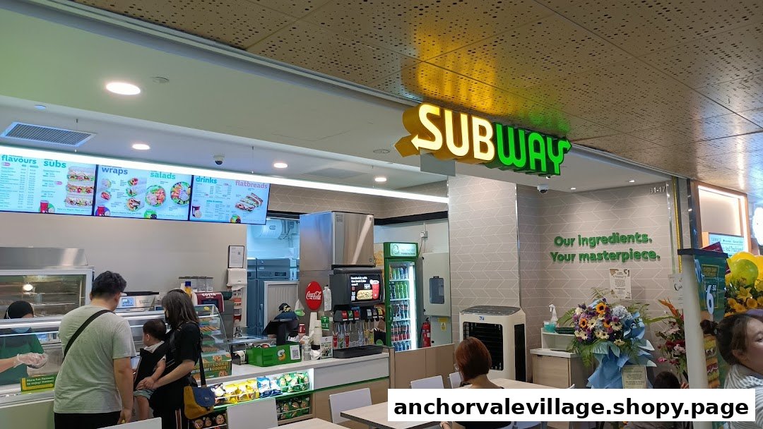 Interior view of a Subway restaurant showing the counter, menu boards, and customers.