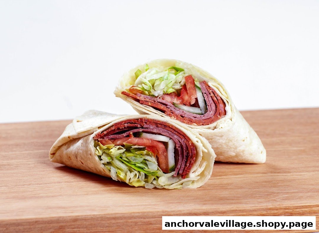 Two halves of a fresh wrap filled with meat, lettuce, tomatoes, and onions.