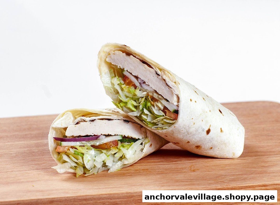 Two halves of a fresh chicken and vegetable wrap on a wooden board.