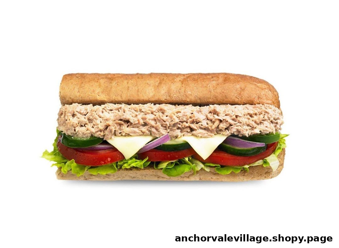A close-up of a Subway sandwich filled with tuna, cheese, and fresh vegetables.