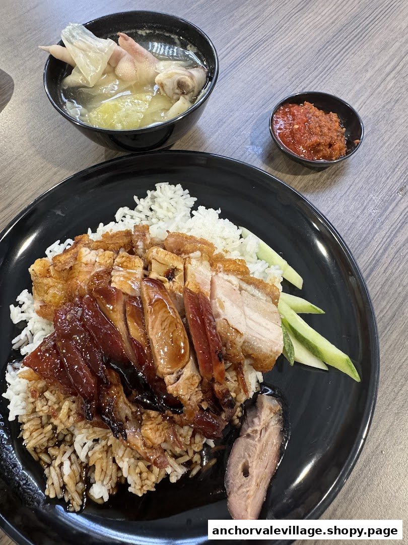 A plate of roasted delights featuring char siew, roasted pork, and duck with rice, soup, and chili.