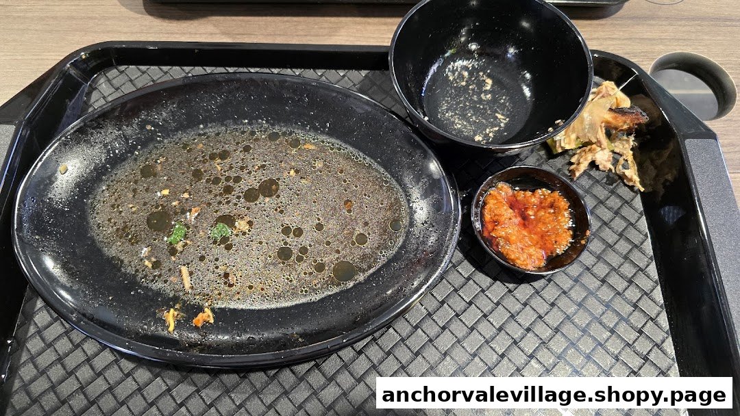 A tray with empty and used dishes, including a bowl of chili sauce, after a meal.