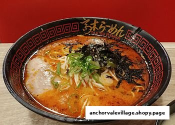 A vibrant bowl of spicy ramen with pork, seaweed, and green onions.