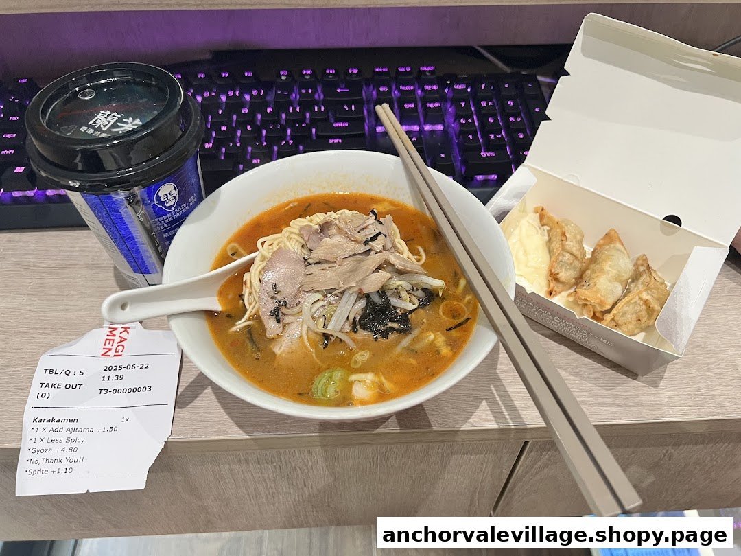 A delicious takeout meal featuring a bowl of ramen, gyoza, and a drink on a desk.