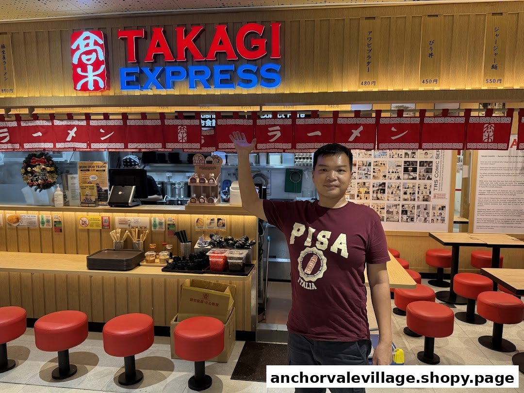 An interior view of Takagi Ramen Express, featuring a customer, counter seating, and a glimpse of the kitchen.