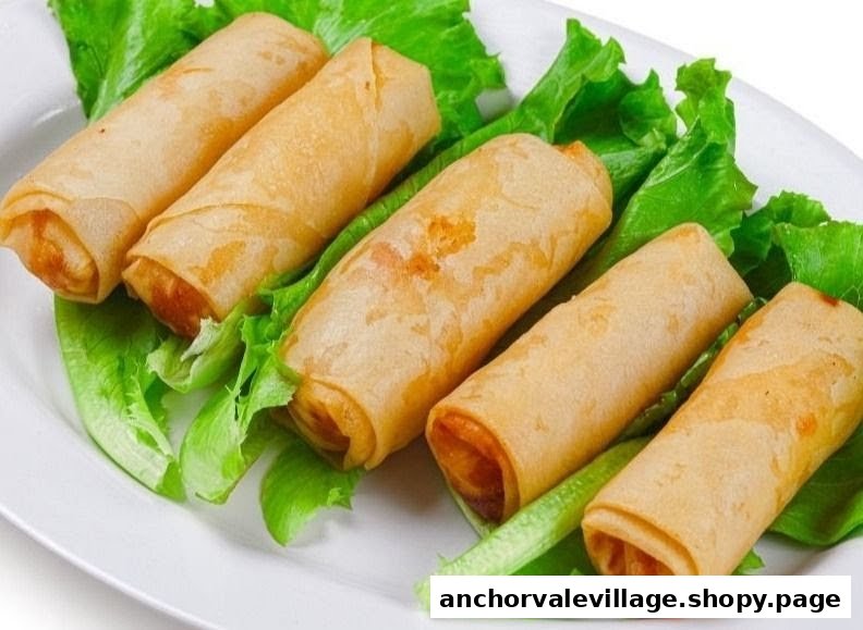 Five crispy golden spring rolls arranged on fresh green lettuce on a white plate.