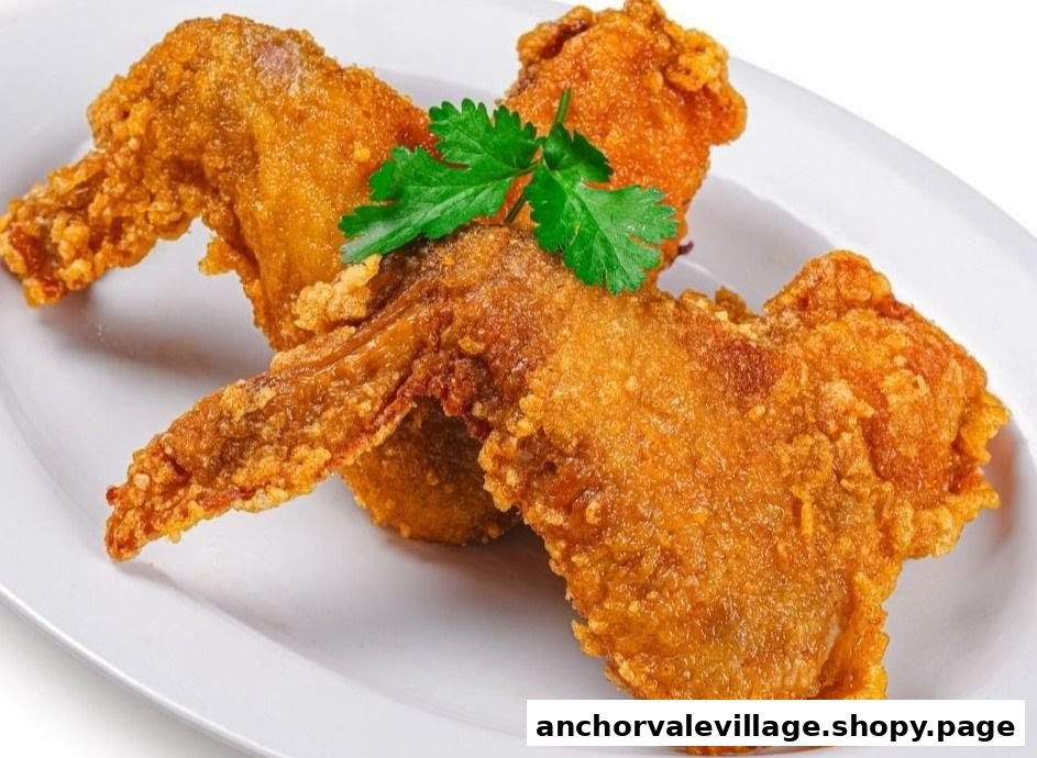 Two golden-brown fried chicken wings garnished with fresh parsley on a white plate.