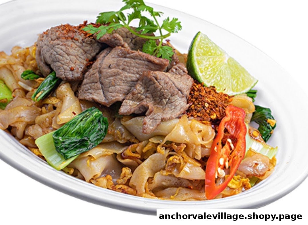A close-up of a Thai noodle dish with beef, bok choy, lime, and chili flakes.