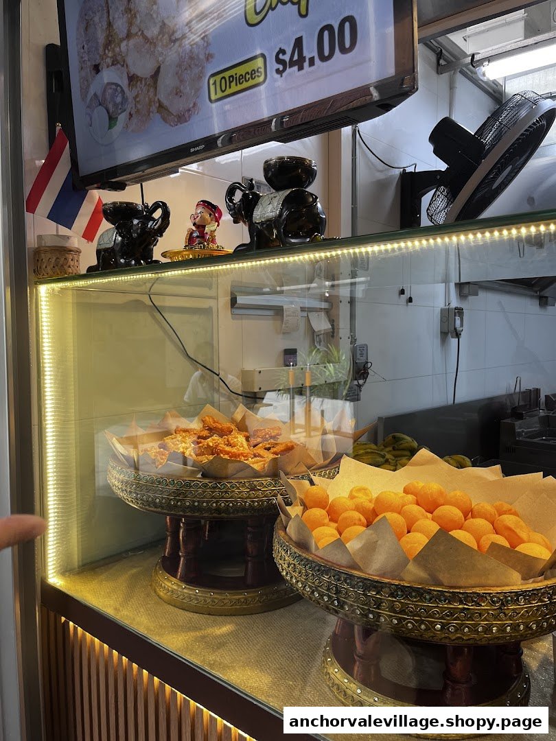 A vibrant display counter showcasing traditional Thai fried snacks and a digital menu screen.