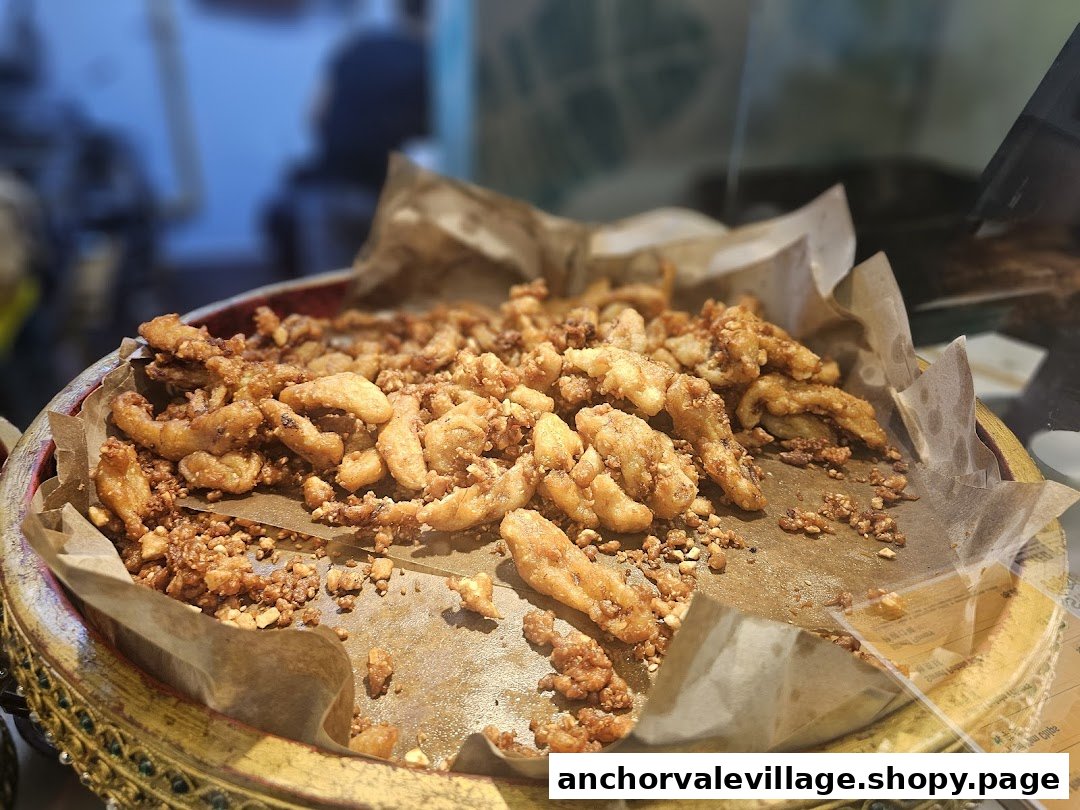 A close-up of golden-fried banana fritters, sprinkled with nuts, displayed on a decorative tray.