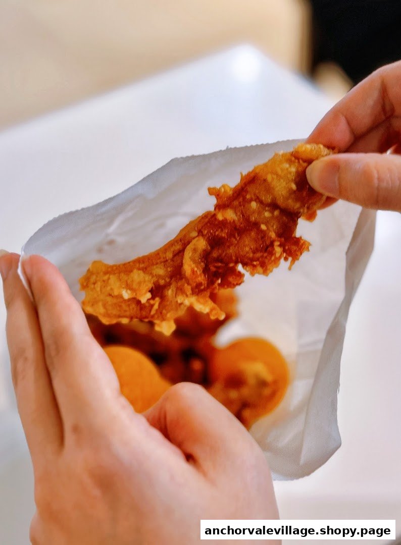 Hands holding a paper bag filled with golden-fried Thai bananas, ready to enjoy.