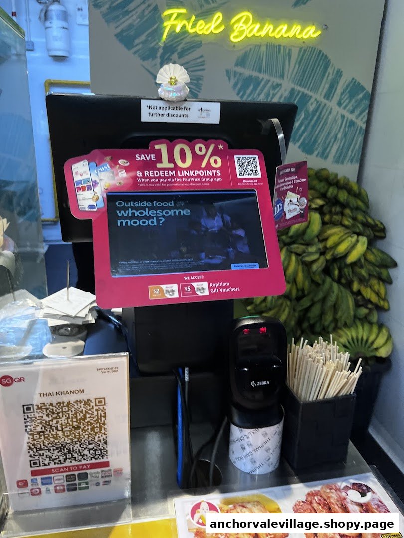 A shop counter featuring payment options, a 'Fried Banana' neon sign, and fresh bananas.