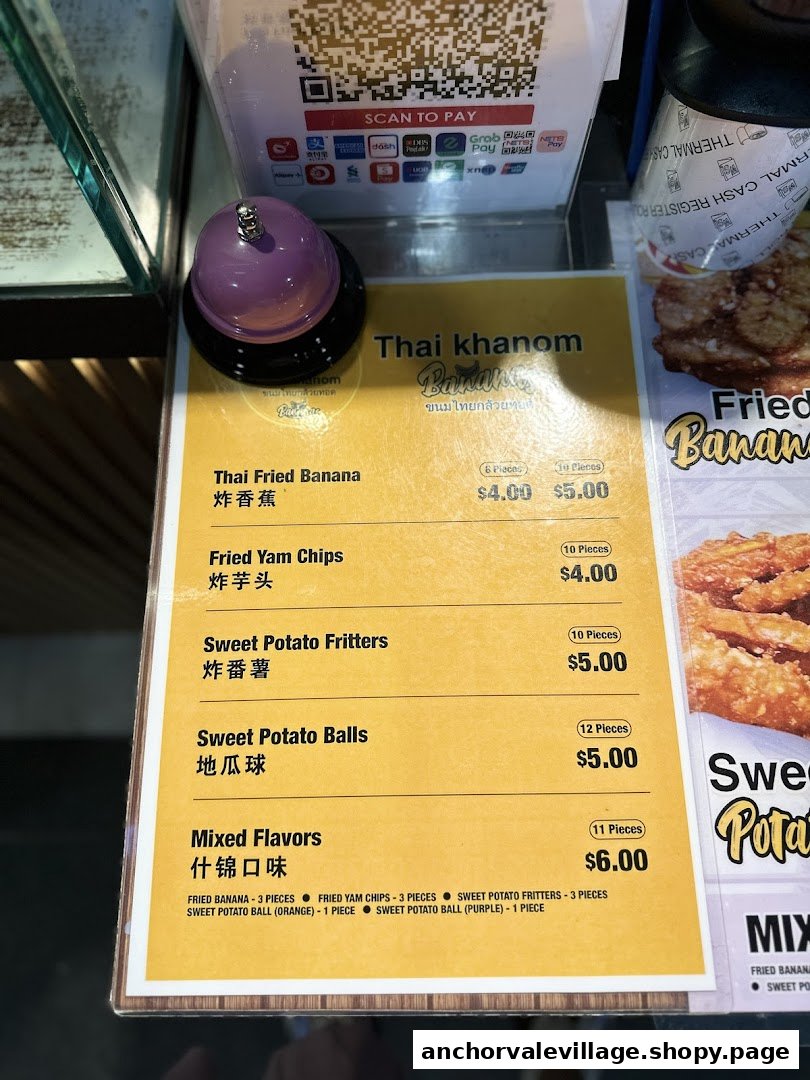 A menu board displaying prices and items for Thai fried bananas, yam chips, and sweet potato snacks.
