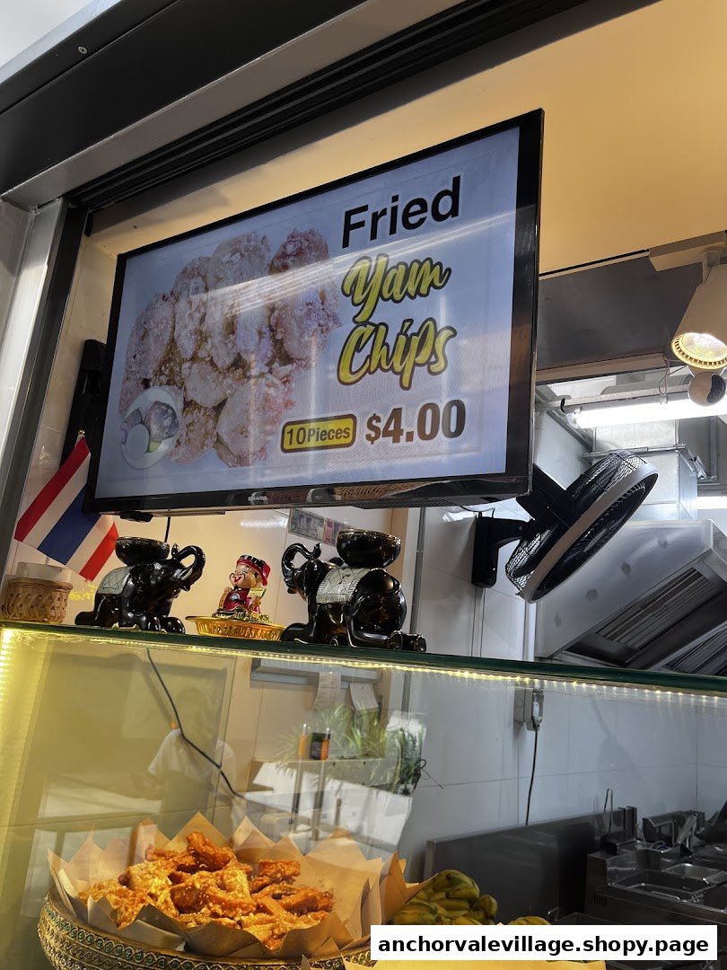A digital display advertises Fried Yam Chips for $4.00 at a Thai snack counter.