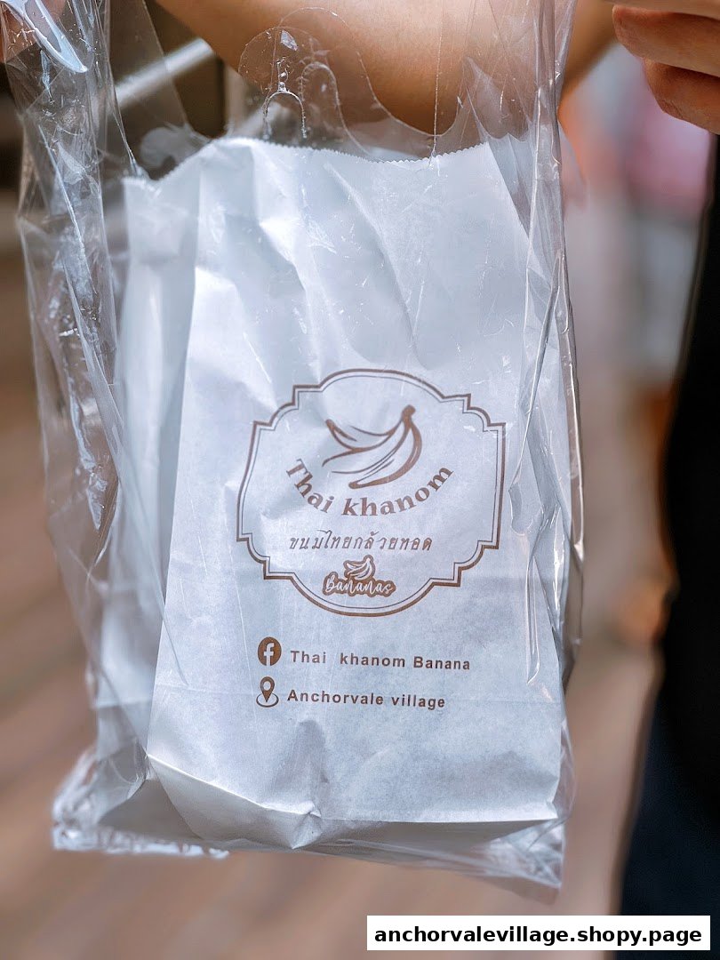 A clear plastic bag with 'Thai Khanom Bananas' branding, held by a person.