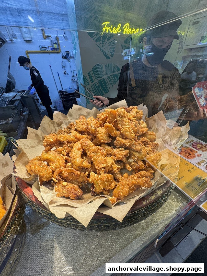 A large display of golden fried bananas at Thai Khanom Bananas, with staff preparing food in the background.