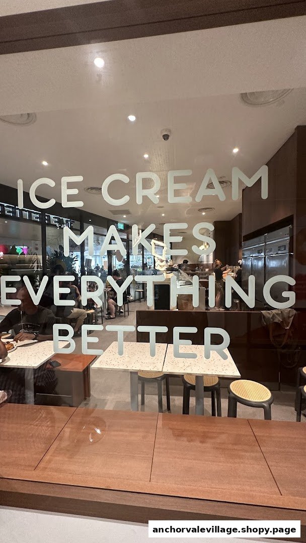 Interior view of an ice cream shop with customers and a window decal stating 'Ice Cream Makes Everything Better'.