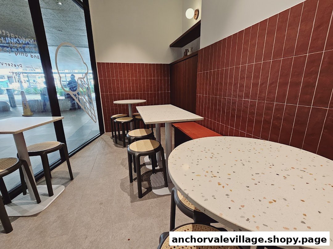 Interior view of The Better Scoop, featuring modern tables, stools, and a tiled wall.