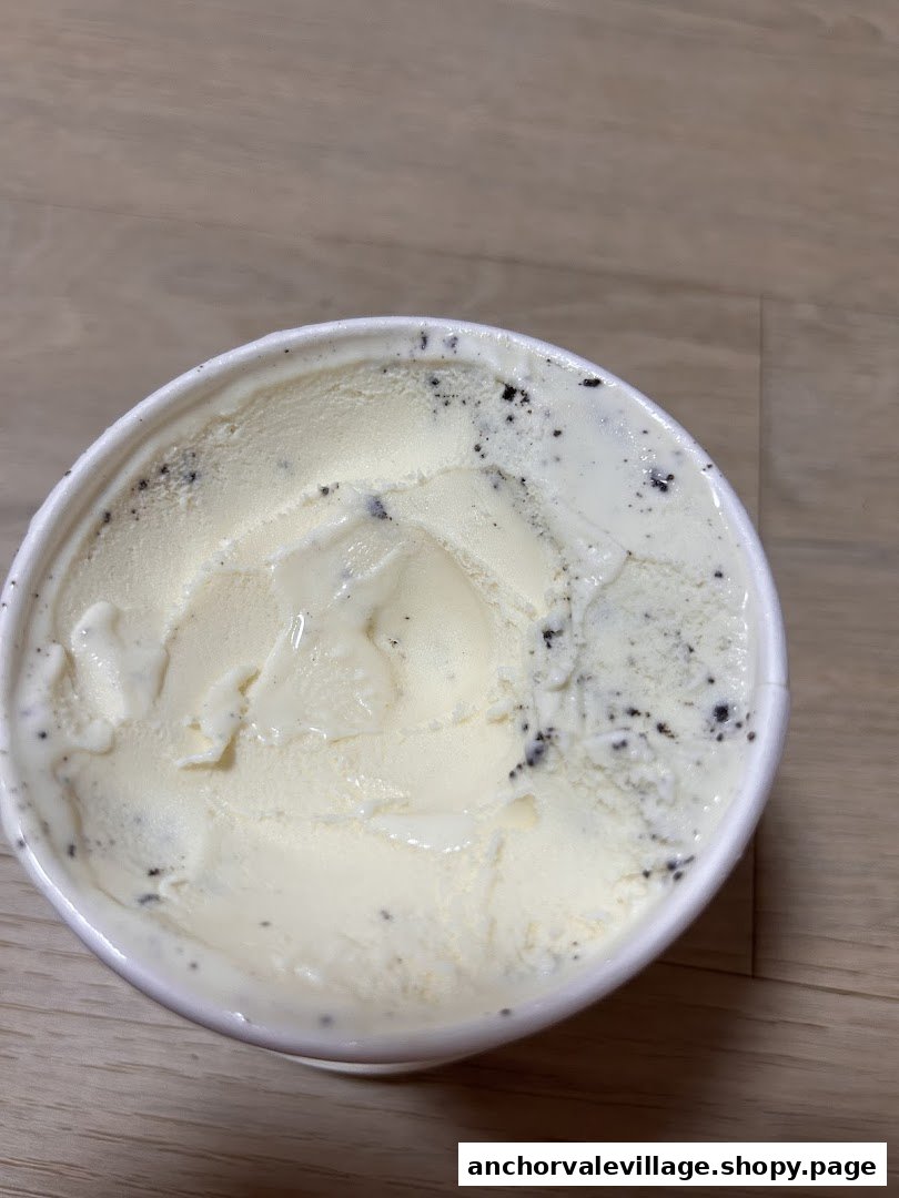 A close-up view of a tub of creamy vanilla ice cream with cookie crumbs.