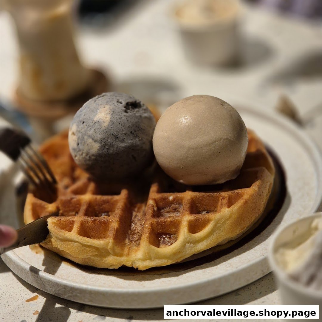 A delicious waffle topped with two scoops of ice cream, being cut on a plate.